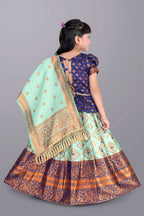 Traditional outfit with a green dupatta and blue and orange skirt on a gray background